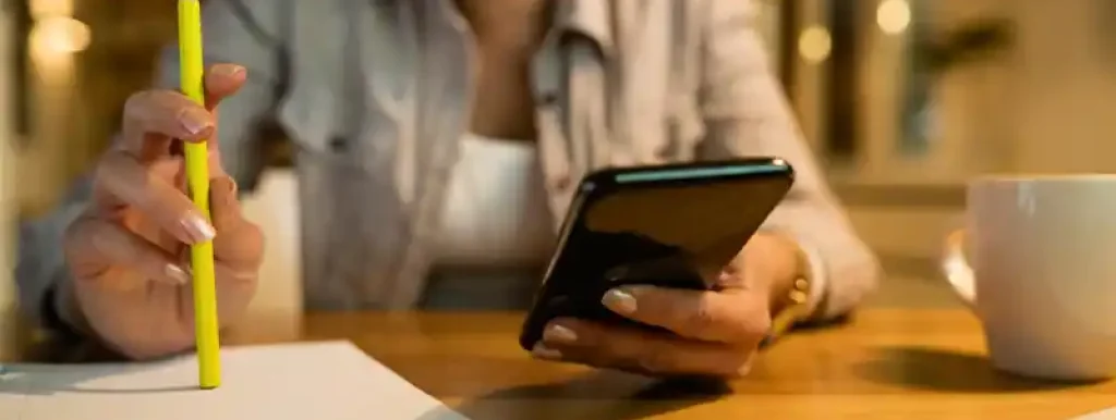 corretora-com-celular-na-mao-analisando-impostos-com-lapis